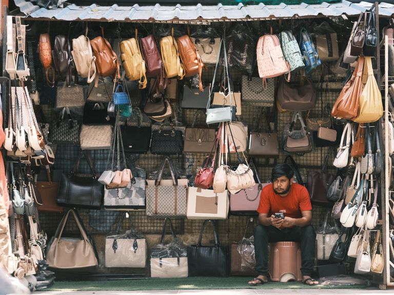 A local vendor selling a variety of bags in a bustling Bengaluru street market.