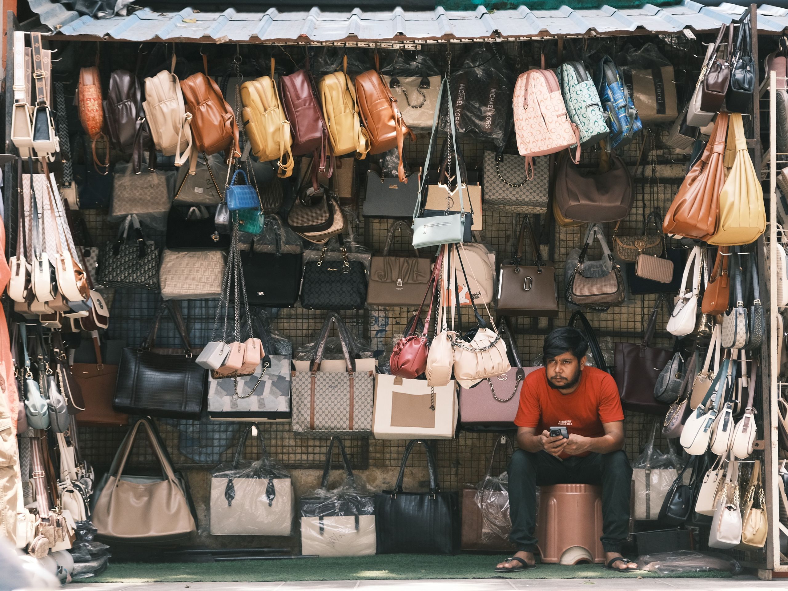 A local vendor selling a variety of bags in a bustling Bengaluru street market.