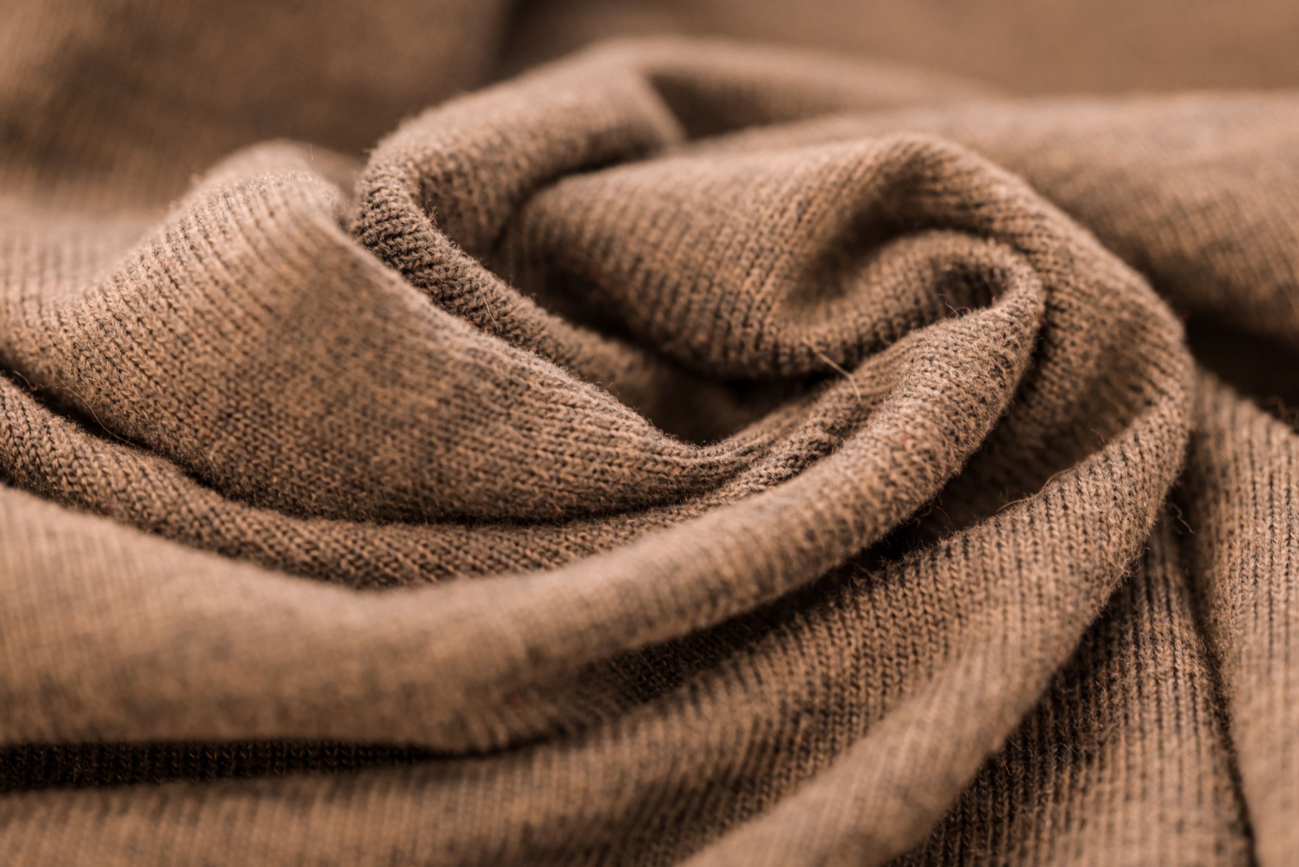 Detailed close-up of a warm brown wool fabric showcasing its soft texture and fine knitting.